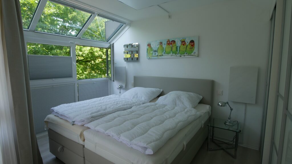 Elternschlafzimmer mit Wintergartenfenstern und Blick ins Grüne